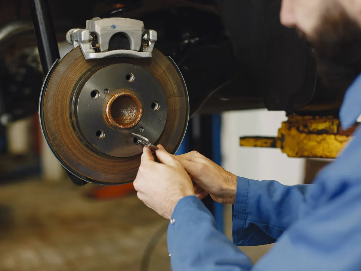 A mechanic working on a brake disc with the wheel removed.